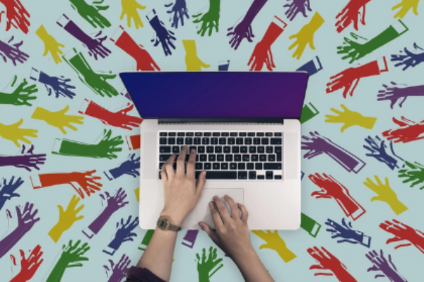 Top view of laptop with female hands on keyboard with a background of different colored hand graphics